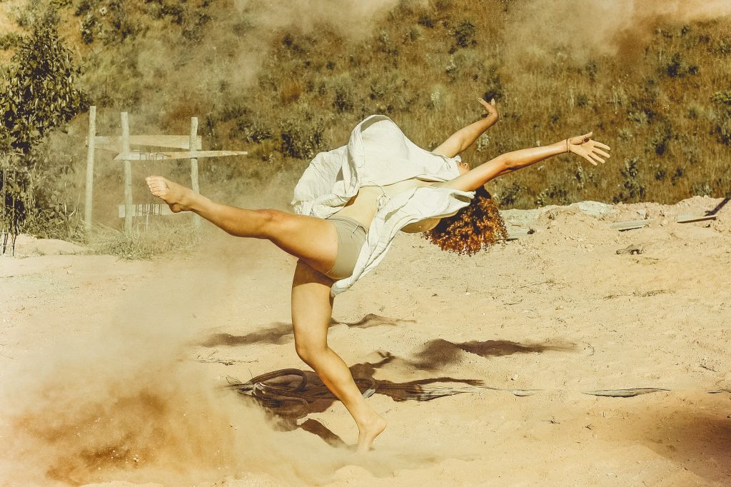 Mulher dançando em um chão de areia.