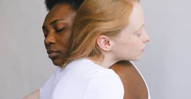 Duas mulheres abraçadas, vistas de perfil.