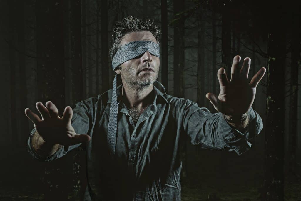 Imagem de um homem representando a situação de um dos atores do filme Bird Box. O homem está com os olhos vendados com a sua gratava cinza.