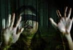 Imagem de um dos atores do filme Bird Box. Ela está com os olhos vendados e com as mãos sobre uma janela de vidro.