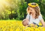Imagem de um lindo campo florido com flores amarelas. Ao fundo uma mãe amamentando o seu filho.
