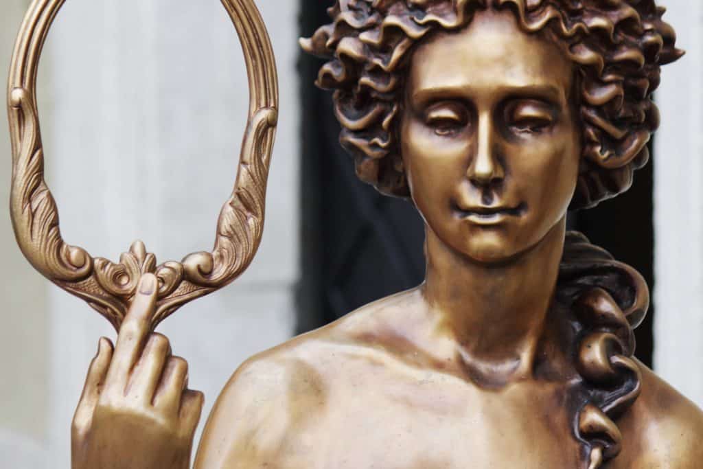 Imagem em bronze da estátua daa deusa Afrodite segurando um espelho.