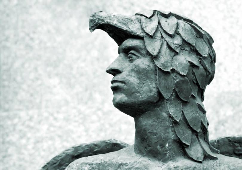 Cabeça da estátua de Ícaro, coberta por uma espécie de escamas com o rosto à mostra. É visível uma pequena parte de suas asas.
