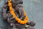 Estátua de Lord Ganesha com um colar de flores laranjas em seu pescoço. Ganesha é um deus com corpo de homem, com quatro braços e a cabeça de elefante.