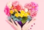 Pessoa contornando com suas mãos um coração feito de flores