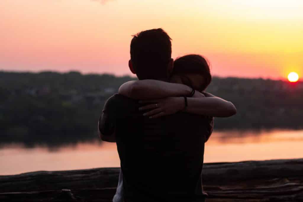 Homem e mulher se abraçando ao lado de um lago