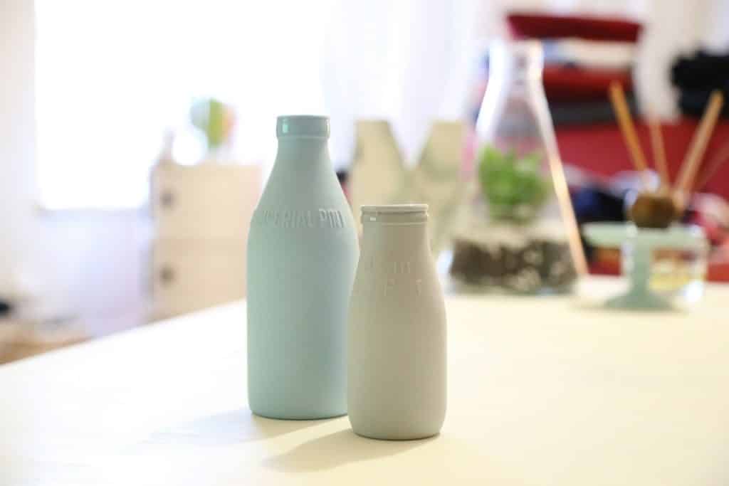 Imagem de duas garrafas plásticas de leite sobre uma bancada.
