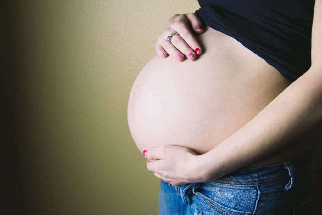 Mulher segurando sua barriga de grávida.