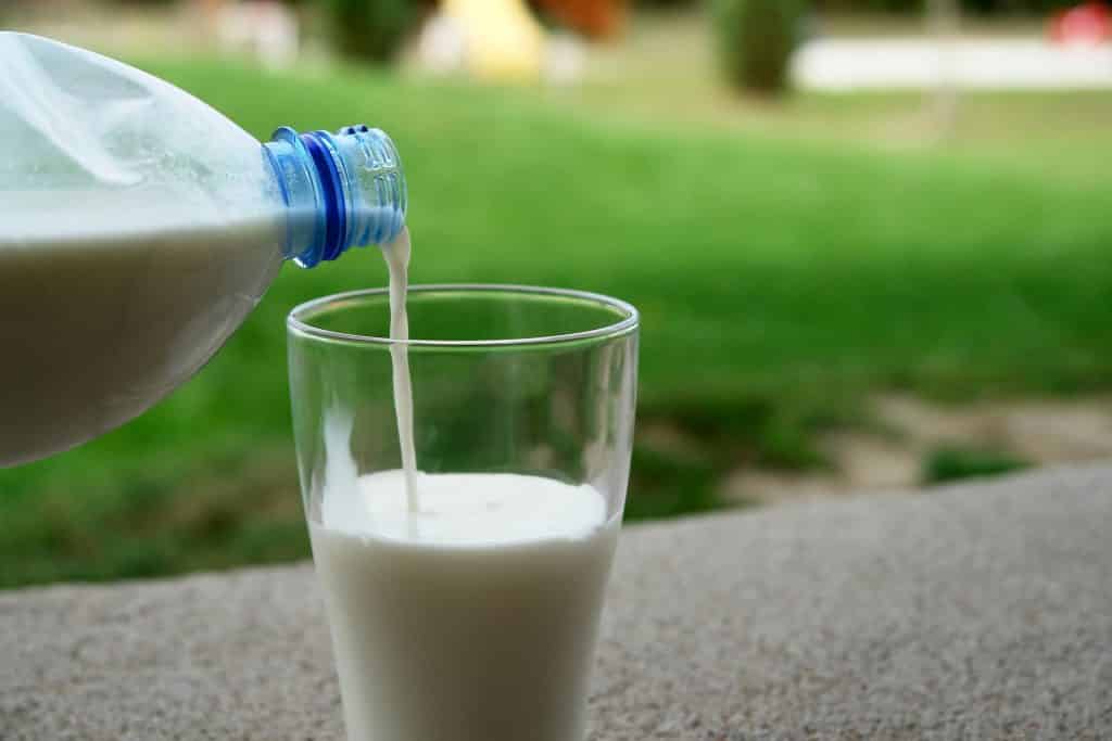 Imagem de um copo de vidro sendo abastecido com leite puro.
