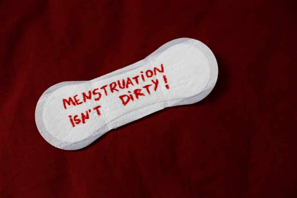 Absorvente branco com letras vermelhas escrito "Menstruação isn't dirty".
