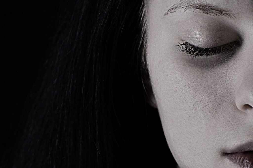 Imagem preto e branco da metade do rosto de uma mulher que está triste e depressiva.