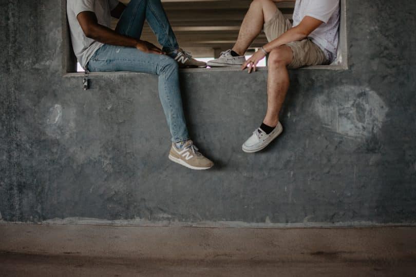 Dois homens sentados em um muro de frente para o outro