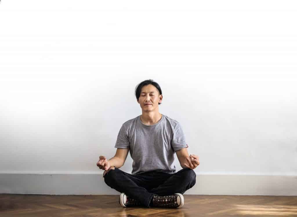 Homem sentado em posição de meditação.