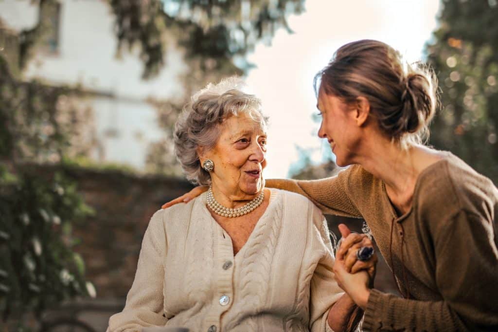 Mãe idosa e sua filha adulta conversando.