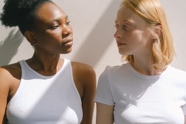 Mulher negra e mulher branca se olhando com expressões sérias