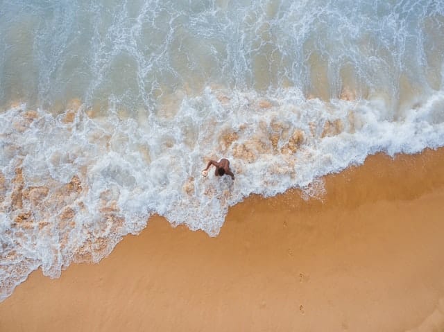 Homem saindo do mar visto de alto 