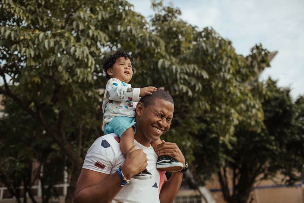 Pai negro com filho levantado em seus ombros