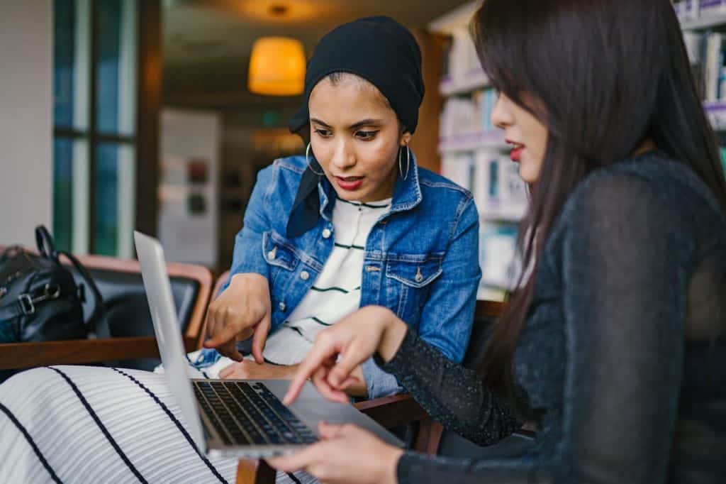 Duas mulheres conversando e olhando um computador.