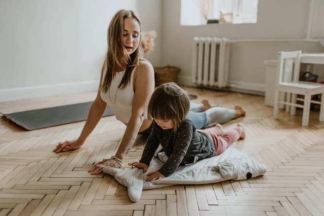 Mãe e filha fazendo exercícios no chão da sala