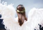 Mulher com asas de anjo de cabelo solto com uma coroa de flores