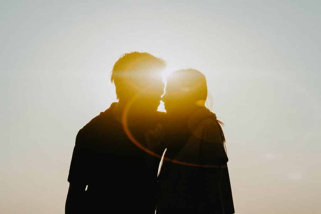 Silhueta de homem e mulher se beijando com a luz do sol