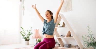 Mulher meditando com as mãos para o auto em uma sala de meditação