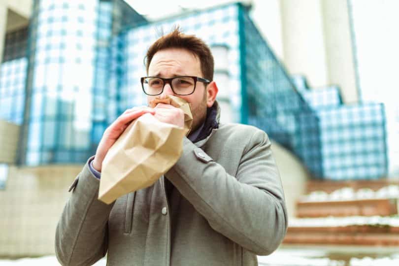 Homem com saco de papel respirando