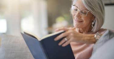 Mulher sentada no sofá lendo livro