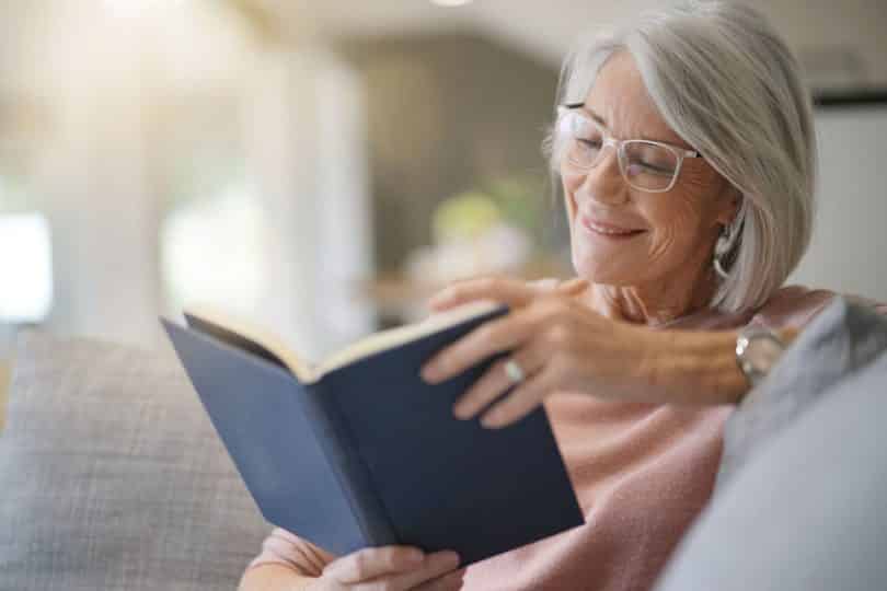 Mulher sentada no sofá lendo livro