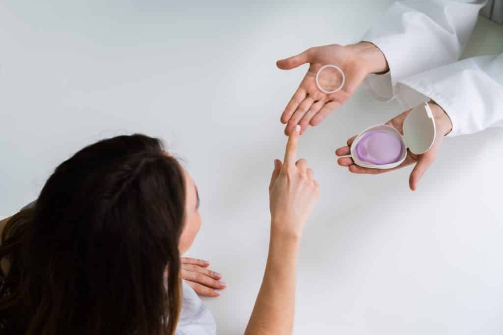 Imagem de uma mulher escolhendo o diafragma contraceptivo. Os doois modelos estão dispostos sobre as mãos de sua médica ginecologista.