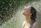 Mulher sorrindo enquanto toma banho de chuva.