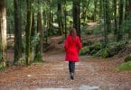 Mulher usando casaco vermelho caminhando numa floresta.