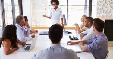 Mulher em pé em sala de reunião liderando