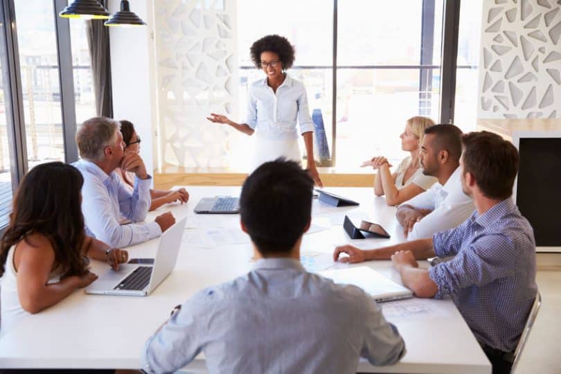 Mulher em pé em sala de reunião liderando