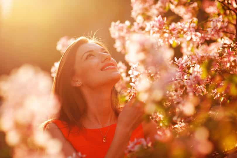 Mulher entre flores com sol refletindo