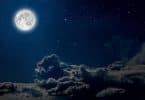 Céu noturno com uma lua cheia e nuvens.