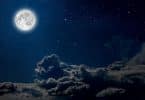 Céu noturno com uma lua cheia e nuvens.