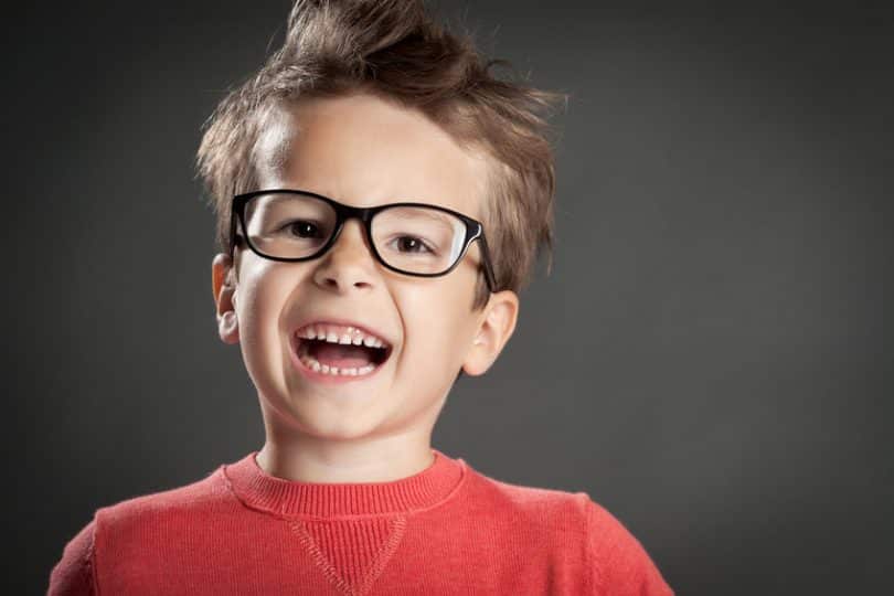 Garoto de suéter vermelho usando óculos sorrindo