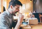 Homem em mesa de restaurante comendo lanche