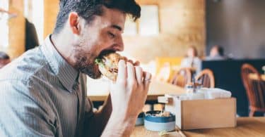 Homem em mesa de restaurante comendo lanche