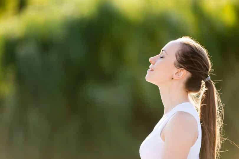 Mulher de perfil com olhos fechados e cabeça para cima com fundo verde