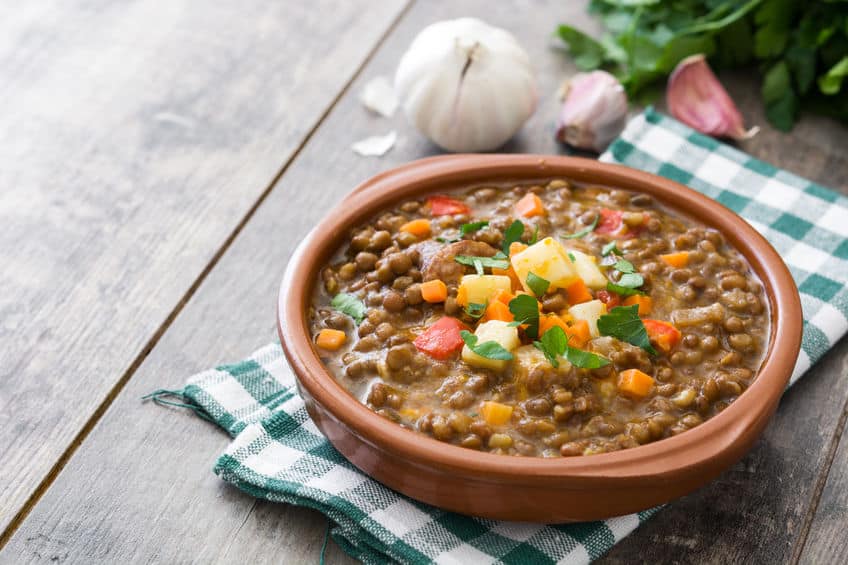 Sopa de lentilha em uma vasilha sobre uma mesa de madeira