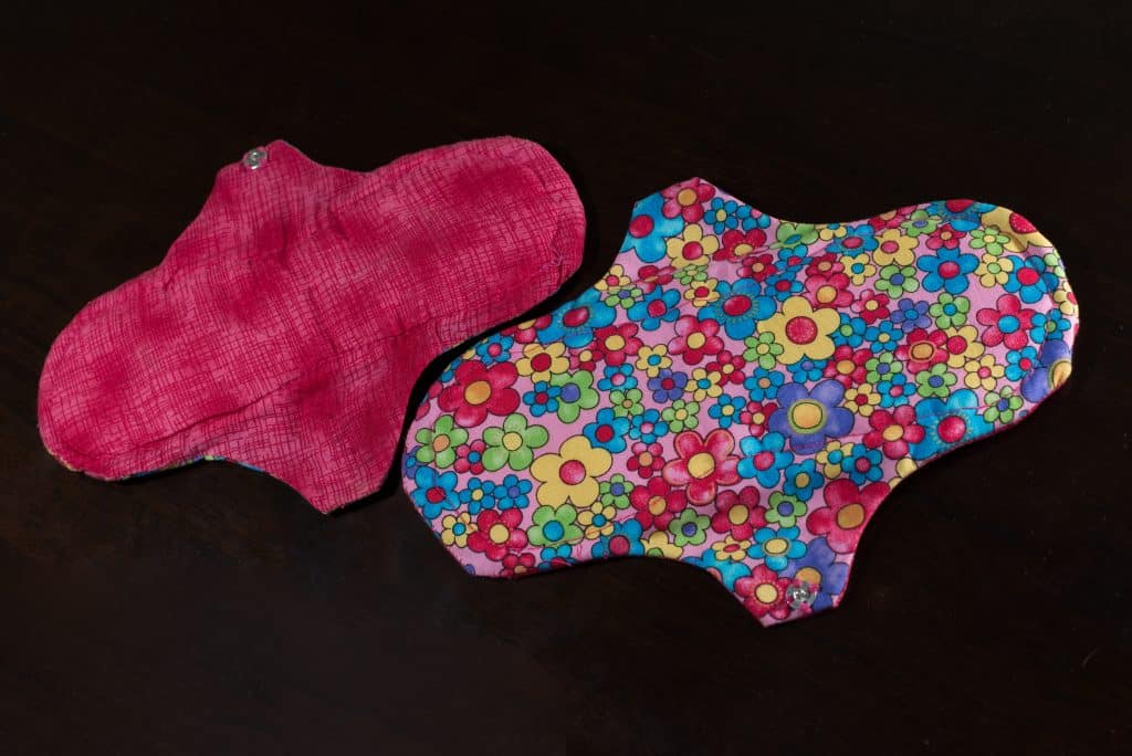 Imagem de um absorvente de pano nas cores rosa e estampada de florzinhas.