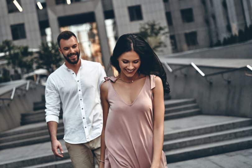 Homem e mulher caminhando juntos pela rua e rindo.