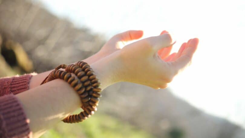 Imagem das mãos de uma mulher com as palmas para cima em sinal de meditação.