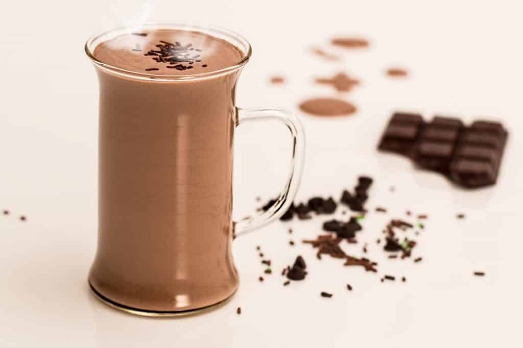 Chocolate quente em uma caneca com uma barra de chocolate ao lado.