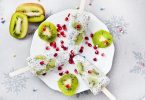 Imagem de três picolés feitos de semente de chia dispostos sobre um prato branco de porcelana decorado com kiwis fatiados.