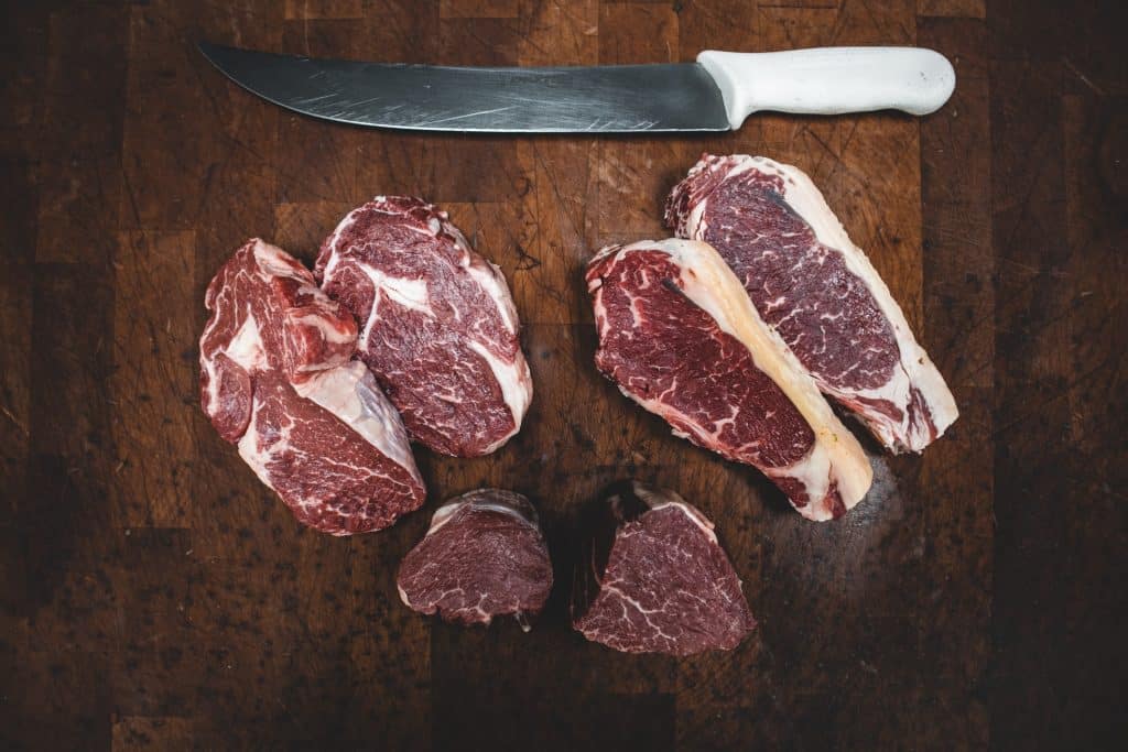 Fatias de carne bovina em cima de uma tábua de madeira.