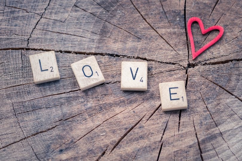 Imagem da palavra amor ecrita em inglês - LOVE - sobre um tronco de madeira e ao lado a imagem de um coração.