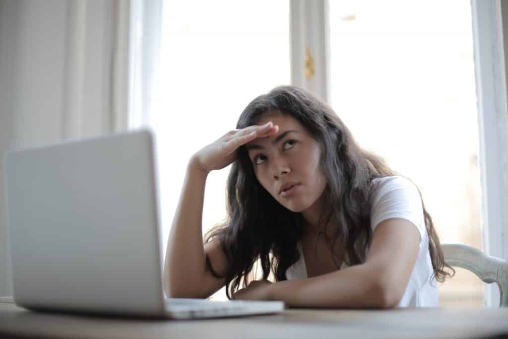 Mulher em frente ao computador com a mão apoiando o rosto